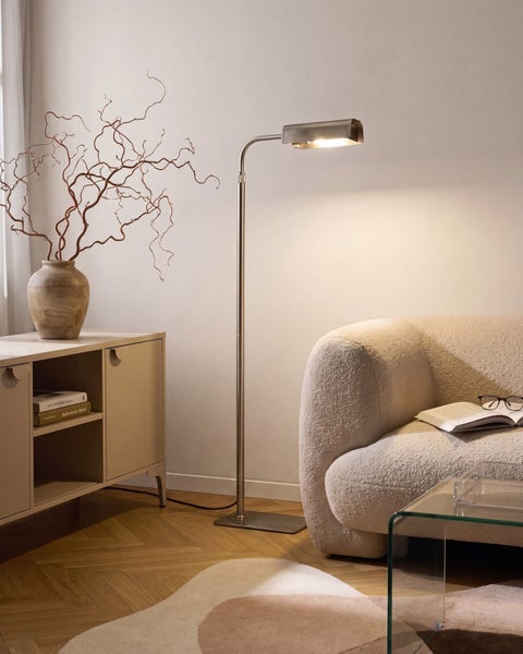 Moderne Stehleuchte mit Metallfuß neben einem strukturierten Sofa in einem wohnlich eingerichteten Raum.