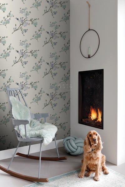 Wohnzimmer mit floraler Tapete, Kamin, Schaukelstuhl und Hund