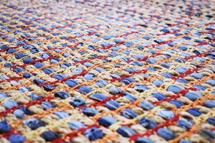 Nahaufnahme eines gewebten Teppichs aus Jute und recycelten Stoffstreifen.