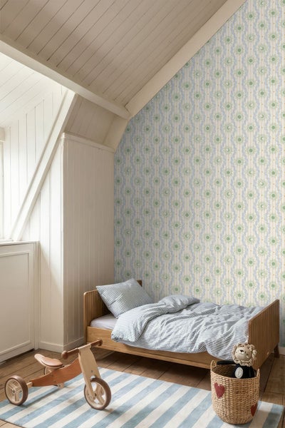 Helles Kinderschlafzimmer mit gemusterter Tapete, Holzbett, gestreiftem Teppich und Spielzeug-Dreirad aus Holz.