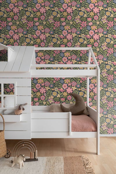 Vliestapete mit Blumenmuster im Kinderzimmer an der Wand hinter einem Hausbett.