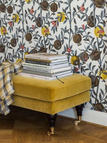 Ansicht eines Wohnzimmers mit orangefarbenem Ecksofa, gemusterten Kissen und einem runden, mehrfarbigen Teppich