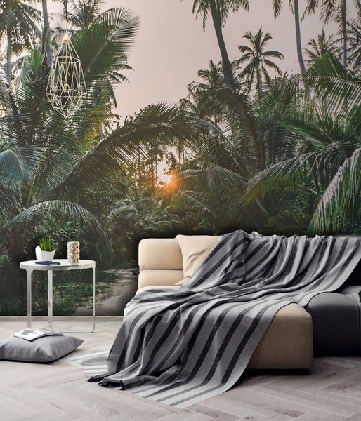 Fototapete mit tropischem Palmenwald bei Sonnenuntergang in einem modern eingerichteten Wohnzimmer.