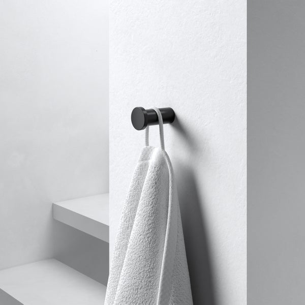 Runder Handtuchhaken an einer Wand mit hängendem Handtuch in einem modernen Badezimmer.