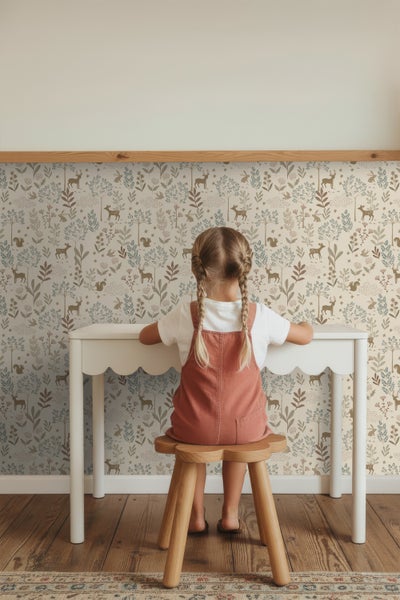 Mädchen sitzt an einem Schreibtisch vor einer Tapete mit Waldmotiven
