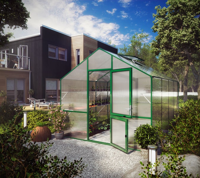 Gewächshaus mit grünem Aluminiumrahmen und Hohlkammerplatten in einem hellen, modernen Garten neben einem Wohnhaus.