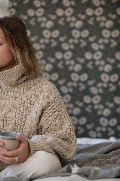 Mann saugt Sofa mit Staubsaugerdüse in hellem Wohnzimmer