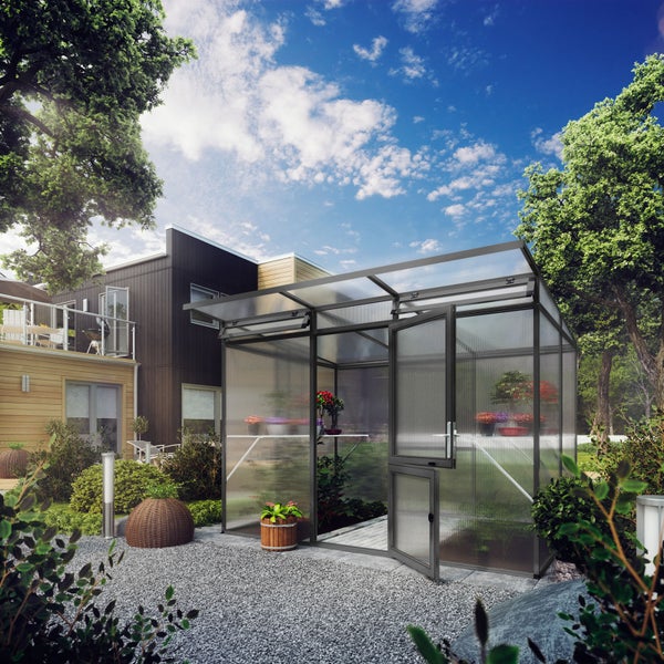 Modernes Gewächshaus aus Aluminium und Hohlkammerplatten mit offener Tür in einem hellen Garten mit Kiesweg neben einem Haus mit Holzfassade.