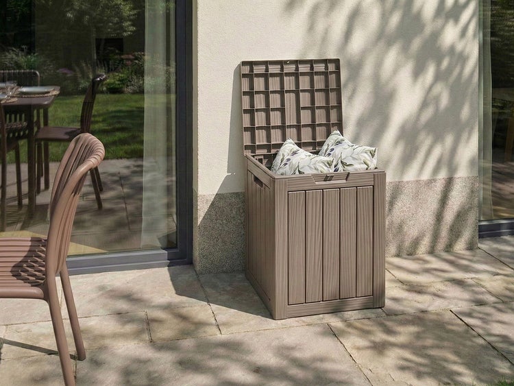 Geöffnete Gartenbox aus Kunststoff mit Kissen auf einer Terrasse