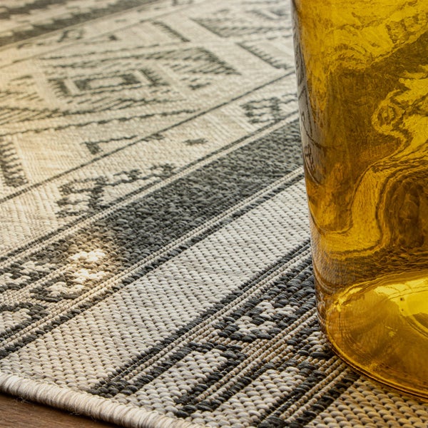 Nahaufnahme eines gewebten Teppichs mit geometrischem Muster und Streifen.