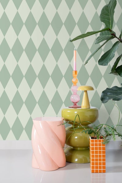 Szene mit Rautenmuster-Tapete, Beistelltisch und Dekorationen.