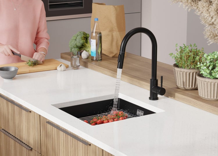 Moderne Küche mit schwarzer Armatur, Spüle und frischen Zutaten