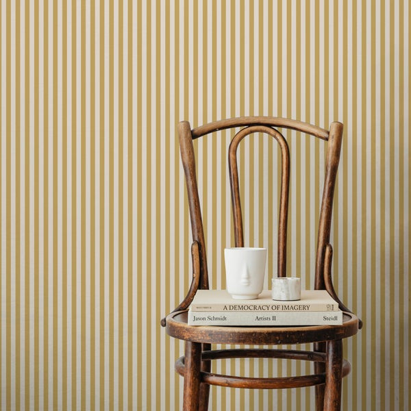 Gestreifte Vliestapete an einer Wand hinter einem Holzstuhl mit Büchern und Dekoration.