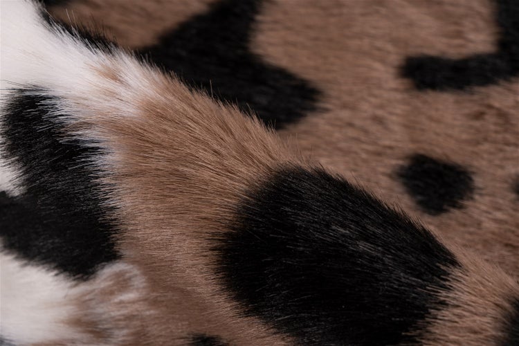 Nahaufnahme eines Teppichs mit Kunstfell-Textur und Tierprint-Muster mit schwarzen und braunen Flecken.