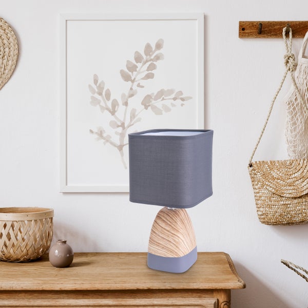 Dekoratives Interieur mit Tischleuchte und Wohnaccessoires auf einem Holzschrank.