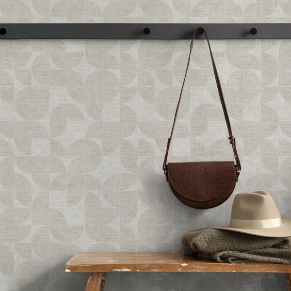 Vliestapete mit geometrischem Kreismuster in Leinenoptik, dargestellt in einem Eingangsbereich mit Holzbank, Tasche und Hut.