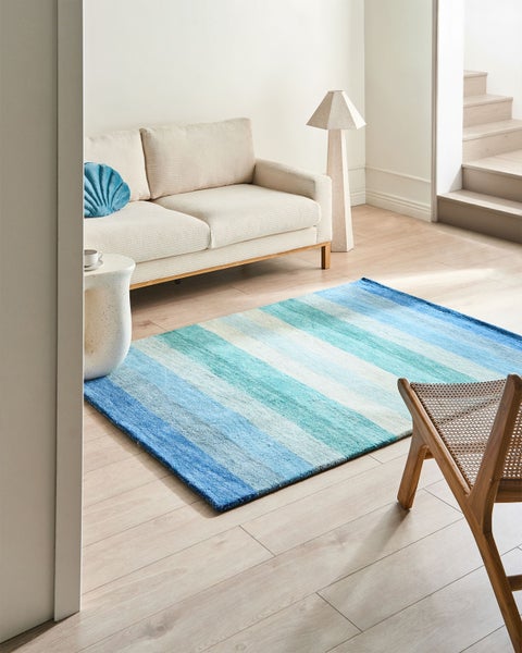 Wohnzimmer mit Sofa, Stehlampe und einem gestreiften Teppich