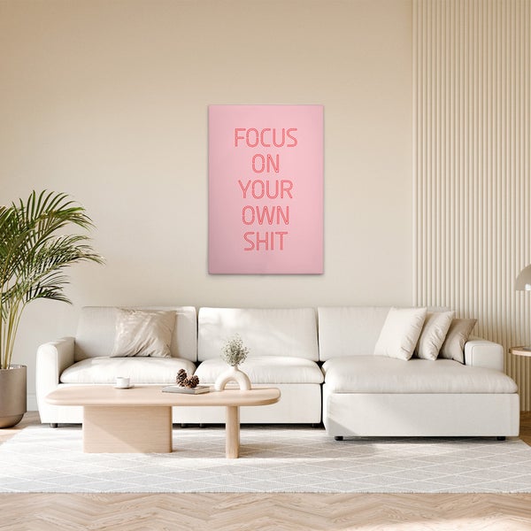Wohnzimmer mit Couch, Tisch und rosafarbenem Wandbild mit dem Text Focus on your own shit