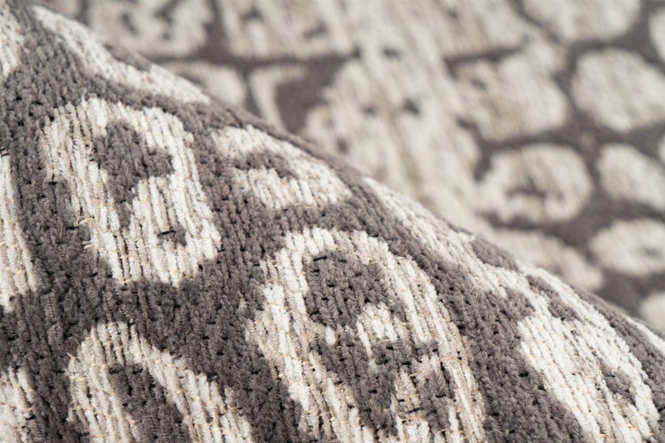 Nahaufnahme eines gewebten Teppichs mit Hoch-Tief-Struktur, Ornamentmuster und weicher Textur.