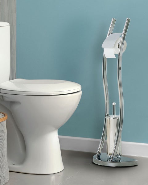 Freistehende Toilettengarnitur aus verchromtem Metall mit Toilettenpapierhalter und Toilettenbürste neben einer weißen Toilette im Badezimmer.