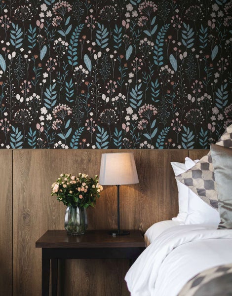 Blumentapete mit filigranem Wiesenblumenmuster in einem stilvoll eingerichteten Schlafzimmer mit Holzkopfteil.