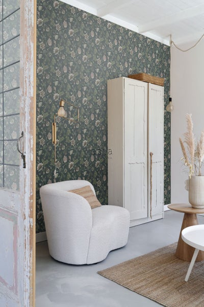 Wohnzimmer mit blumiger Tapete, Sessel, Kleiderschrank und Teppich für eine gemütliche Atmosphäre