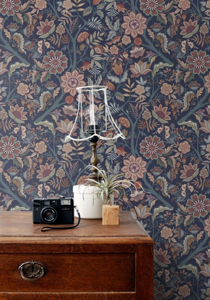 Dekorative florale Tapete mit Vintage-Muster in einem Zimmer mit Lampe und Möbeln.