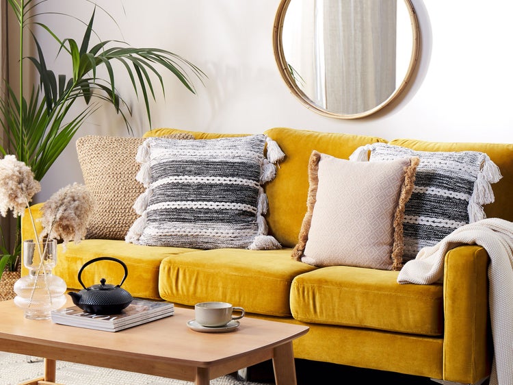 Wohnzimmer mit gelbem Sofa, Kissen, Couchtisch und Dekorationen für eine gemütliche Atmosphäre