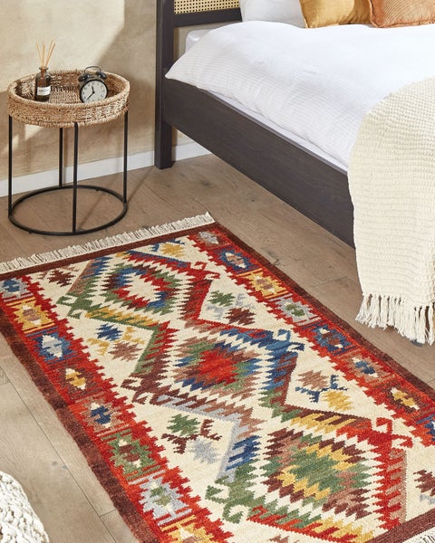 Gemusterter Teppich im Schlafzimmer neben Bett und Beistelltisch
