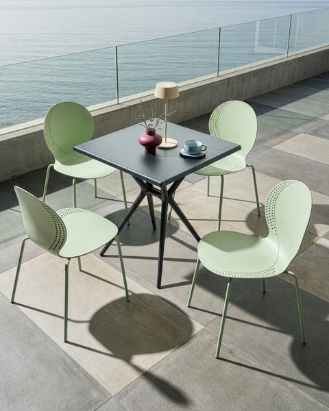 Quadratischer Tisch mit vier Stühlen auf einer Terrasse mit Meerblick