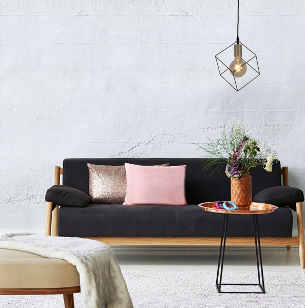 Wohnzimmer mit Sofa, Kissen, Beistelltisch, Lampe und Dekoration