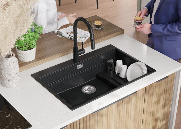 Schwarze Küchenspüle mit Abtropffläche und Wasserhahn auf einer Küchentheke