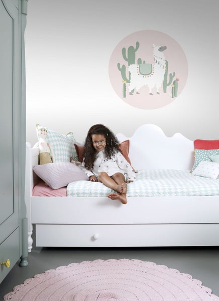 Kinderzimmer mit Bett, Teppich und Wandbild mit Lama-Motiv