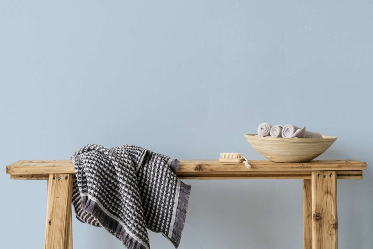 Rustikale Holzbank mit Waffelstruktur-Handtuch, Holzschale mit Rollhandtuechern und Nagelbuerste in einer hellen, organisierten Umgebung.
