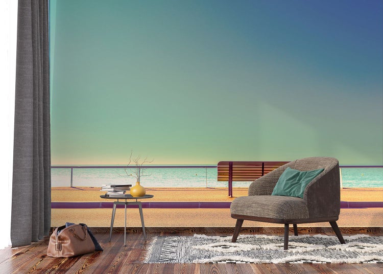 Wohnszene mit Sessel, Tisch, Dekoration, Teppich und Strandtapete für eine helle und freundliche Atmosphäre.