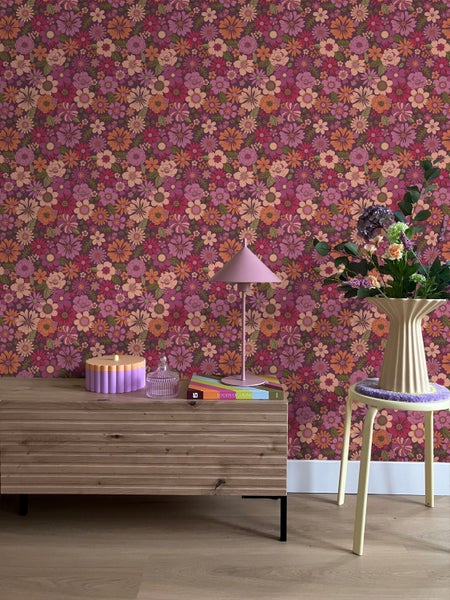 Szene mit blumiger Tapete, Kommode, Lampe, Blumenstrauß und Hocker