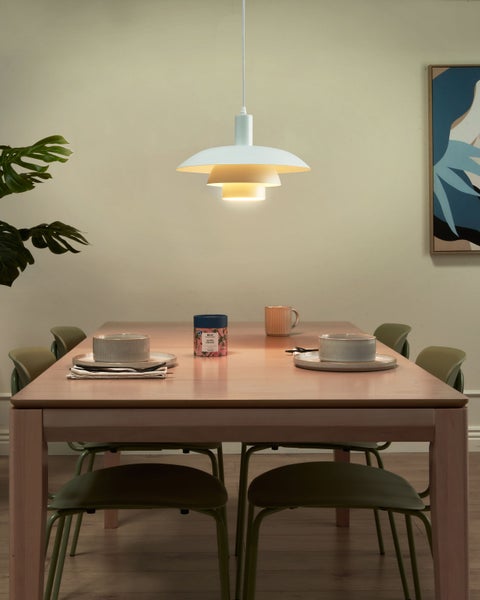 Esstisch mit Gedeck, Pendelleuchte und Dekorationsartikeln in einem Esszimmer.