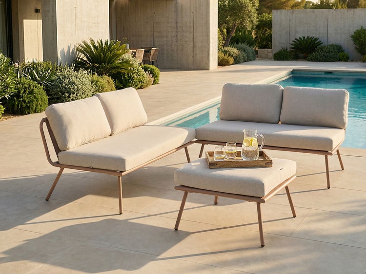 Modernes Lounge-Set aus Metall mit Polstern, bestehend aus zwei Gartensofas und einem Hocker auf einer Terrasse an einem Pool.