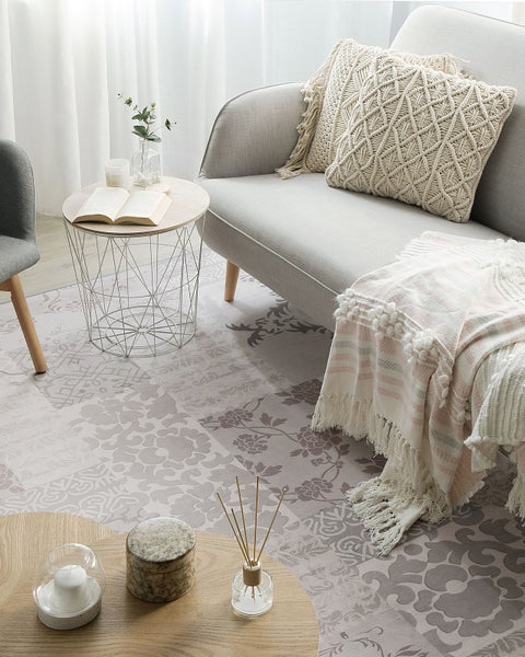 Wohnzimmer mit gemustertem Teppich, Sofa, Beistelltischen und dekorativen Elementen für eine gemütliche Atmosphäre