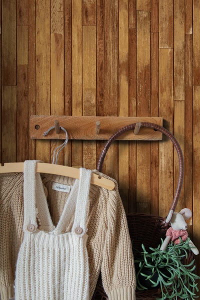 Kinderkleidung an Garderobe mit Korb und Stoffmaus