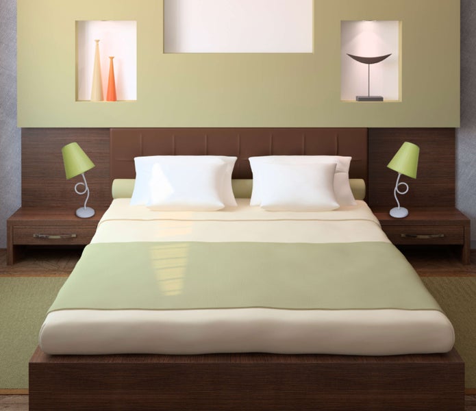 Ein Schlafzimmer mit einem Holzbett, Nachttischen und Lampen.