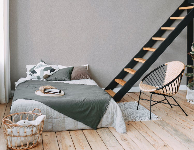 Schlafzimmer mit Bett, Leiter, Korbsessel und Holzboden