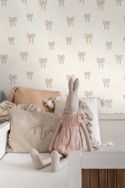 Dekoratives Kinderzimmer mit Schleifenmuster-Tapete und Stofftier-Hase auf dem Bett