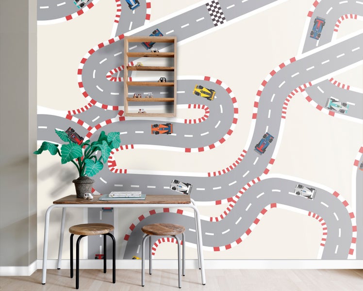 Kinderzimmer mit einer Tapete, die eine Rennstrecke mit verschiedenen Spielzeugautos darstellt, einem Holzbücherregal mit Spielzeugautos, einem Schreibtisch, zwei Hockern und einer Zimmerpflanze
