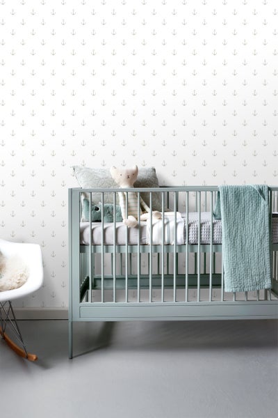 Babyzimmer mit Babybett und Anker-Tapete