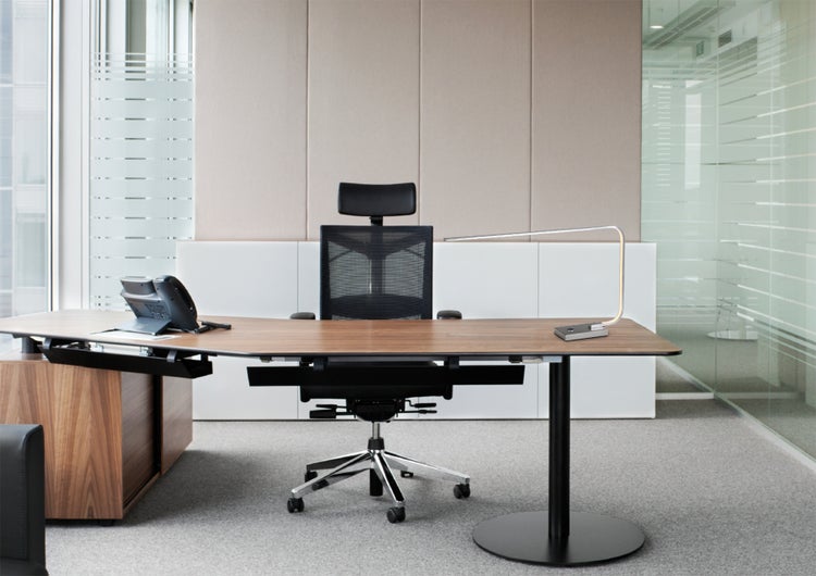 Büroarbeitsplatz mit Schreibtisch, Bürostuhl und Schreibtischlampe in einem modernen Büro