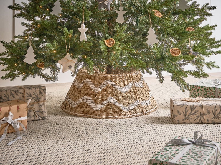 Geschmückter Weihnachtsbaum mit Baumständer aus Naturfasern und Geschenken