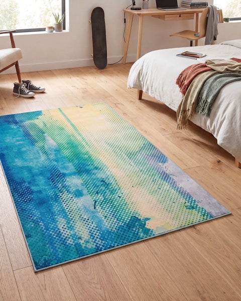 Rechteckiger Teppich mit abstraktem Punktmuster in einem hellen Schlafzimmer auf einem Parkettboden mit Bett und Schreibtisch im Hintergrund.