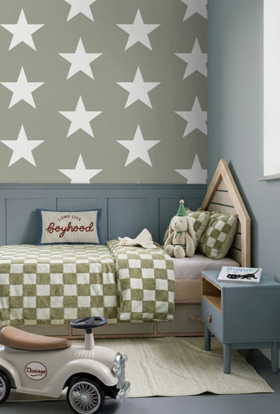 Kinderzimmer mit Stern-Tapete, einem Hausbett aus Holz, karierter Bettwäsche, einem Nachttisch und einem Spielzeugauto im Vintage-Stil.