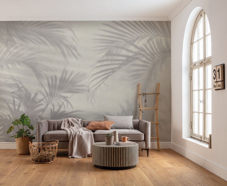 Wohnzimmer mit Sofa, Couchtisch und Wanddekoration mit Schattenmotiven